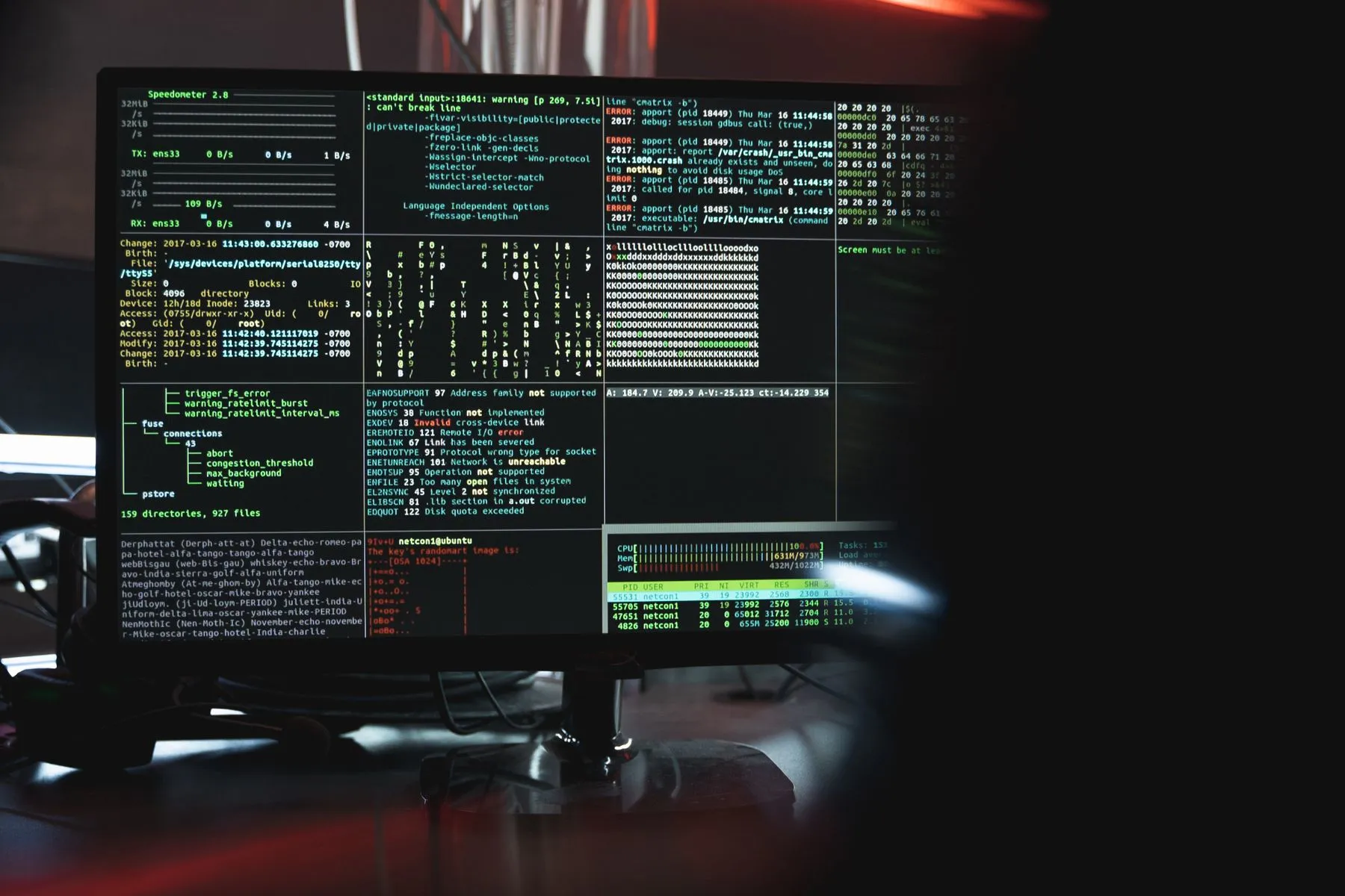 Monitors showing terminal windows and code in a dark room